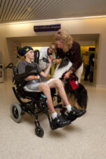 A volunteer and her therapy dog visit with a patient and his aunt at the U-M Health System.
